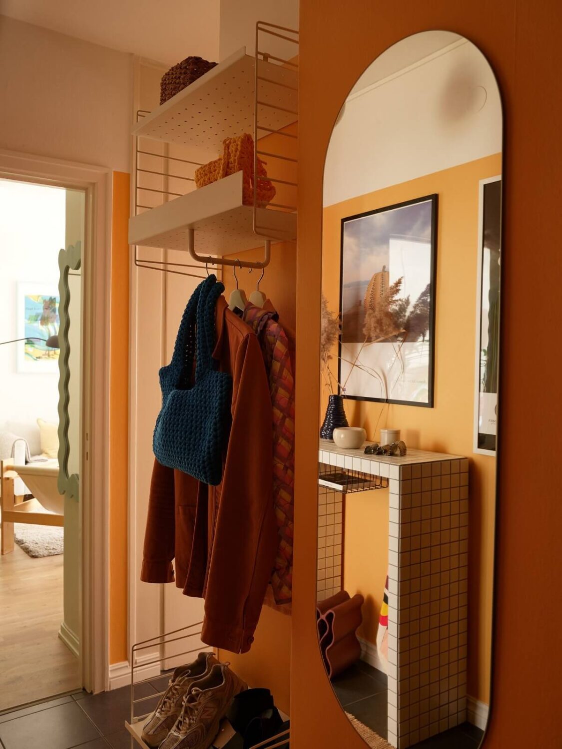A Small Light Filled Apartment with Plants and Color 20 small hallway with orange wall and large wall mirror nordroom