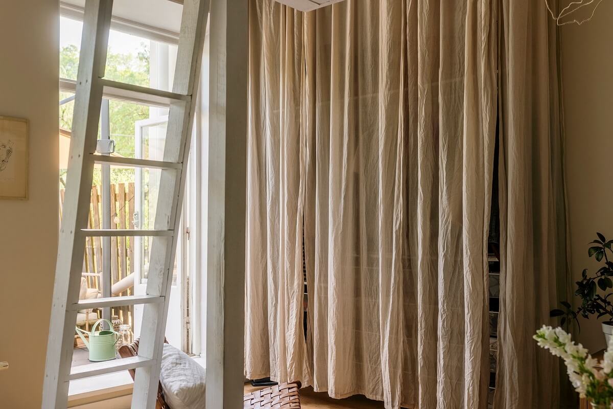 A Charming Studio Apartment with a Loft Bed 6 storage behind curtain in studio apartment