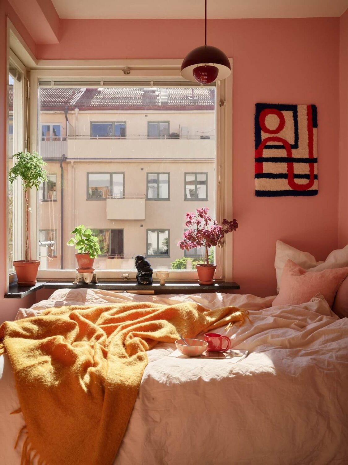 A Small Light Filled Apartment with Plants and Color 13 sunny pink bedroom with ochre yellow throw nordroom