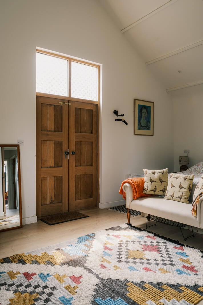 A Black Barn House with Boho Interiors and Breathtaking Views 9 bedroom pitched ceiling colorful rug