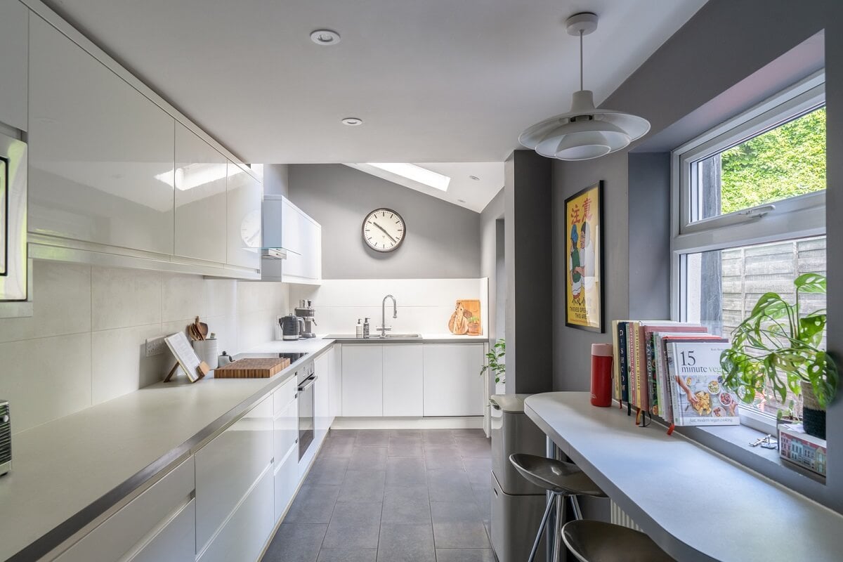 Blue Tones in a Two-Bedroom Victorian Cottage 9 kitchen with white cabinets and window bar seating