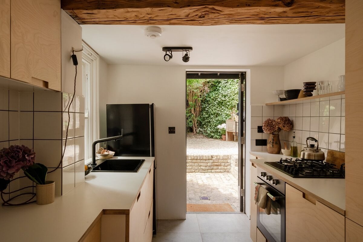 Pared Back Interiors and Light-Filled Spaces in a London Apartment 6 kitchen with wooden cabinet and white tiles