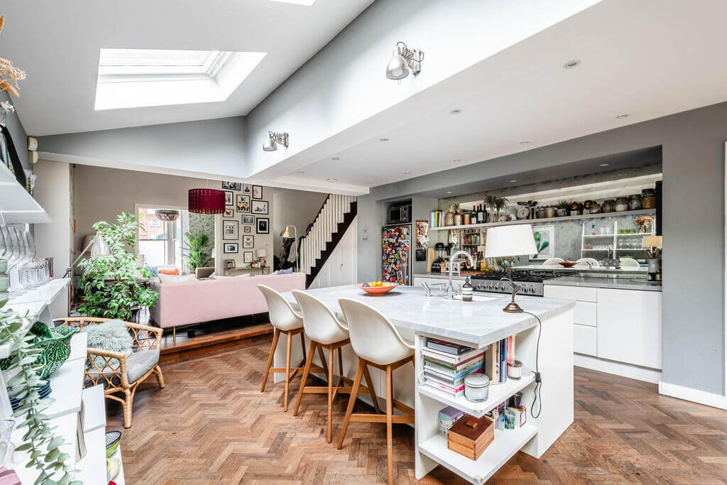 Why Everyone’s Adding Mirrors to Their Kitchens (And You Should Too) 5 kitchen with wooden floor and island with bar seating Why Everyone’s Adding Mirrors to Their Kitchens (And You Should Too)