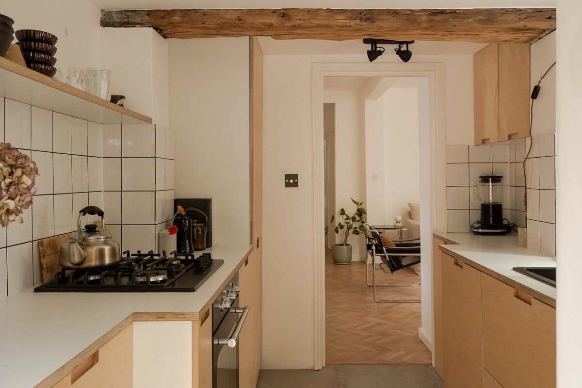 Pared Back Interiors and Light-Filled Spaces in a London Apartment 7 light wooden cabinets white tiles and wooden ceiling beam
