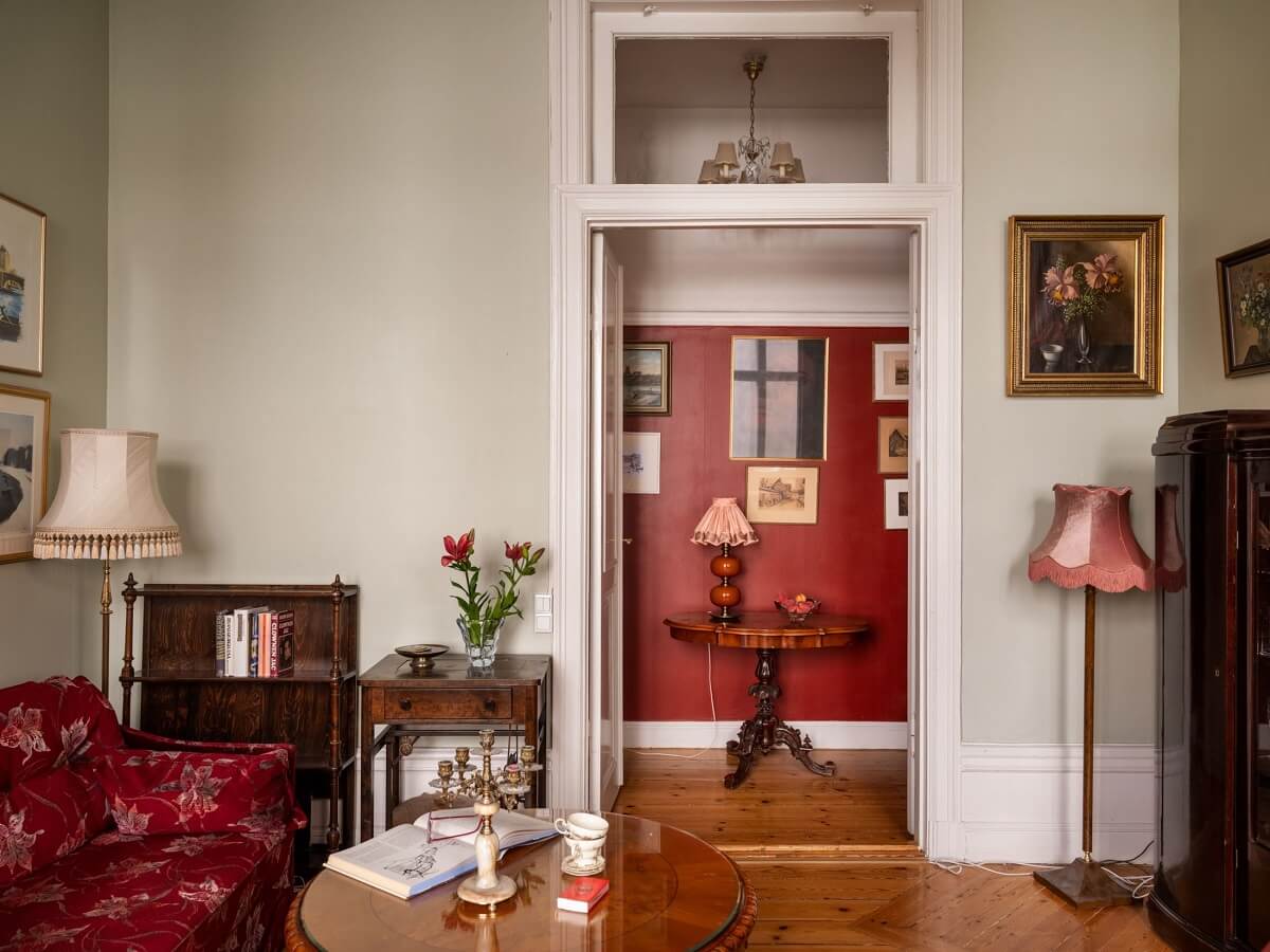 Antique Furniture and Arched Windows in a Stockholm Apartment 8 living room with view into red hallway nordroom