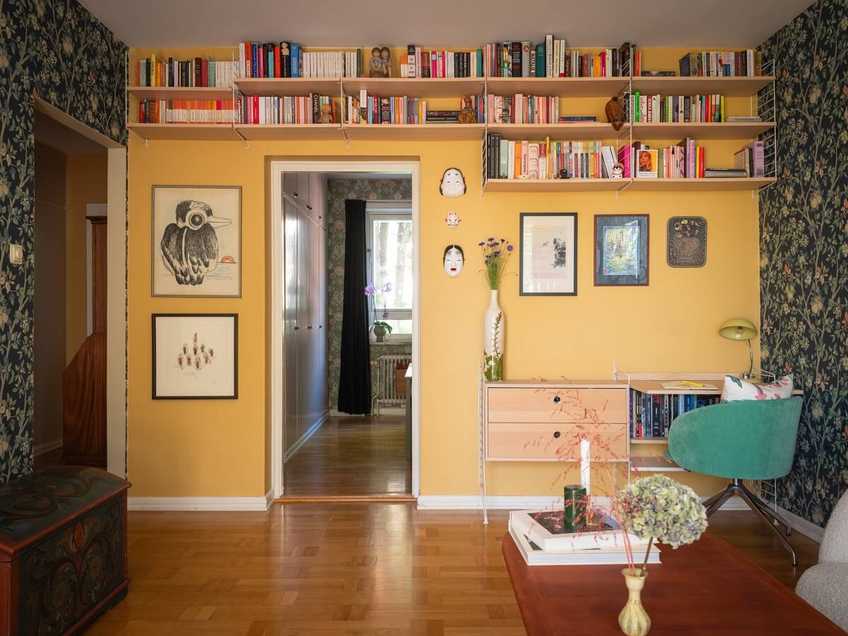Floral Wallpaper and a Pink Kitchen in a Midcentury Apartment 7 living room with yellow accent wall and bookshelves home office