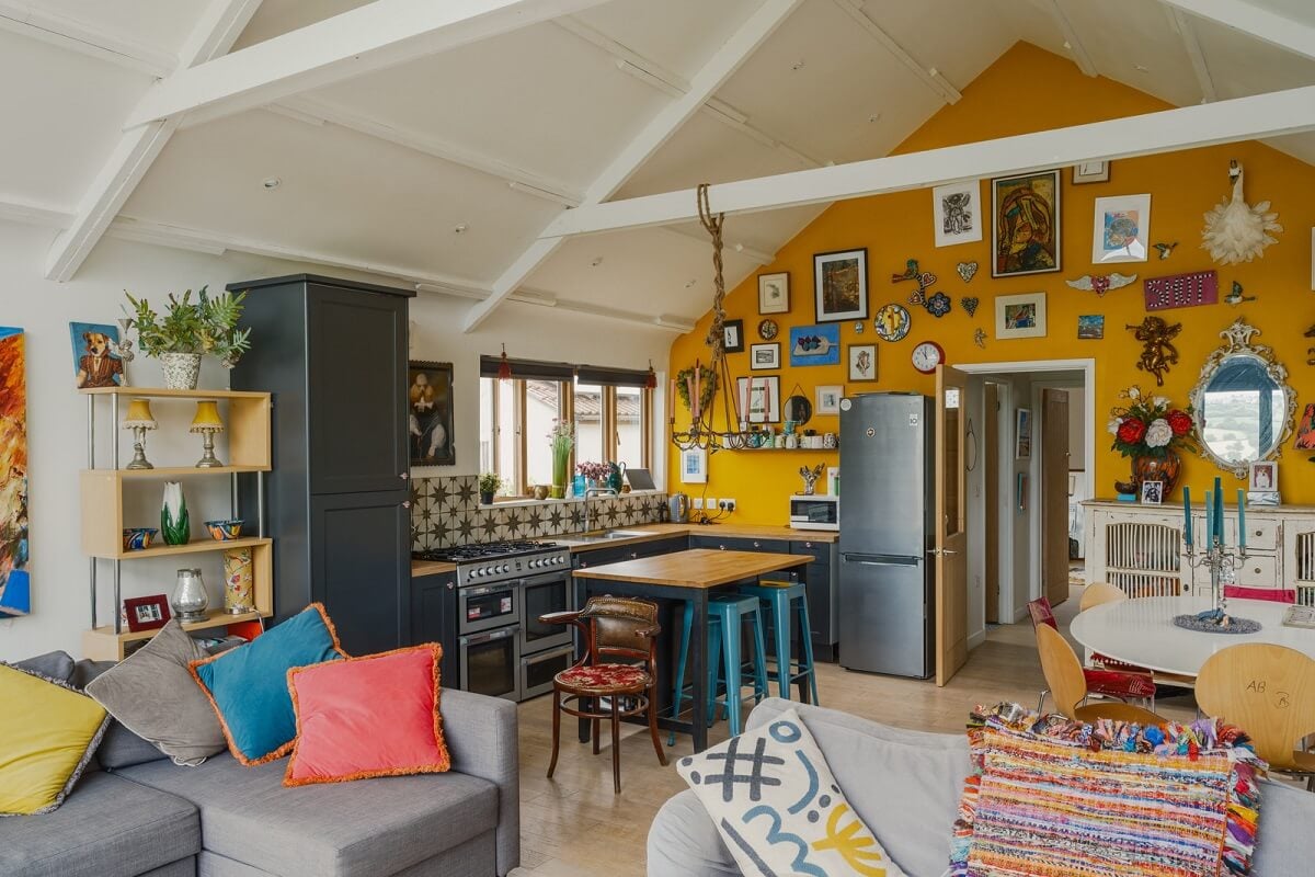 A Black Barn House with Boho Interiors and Breathtaking Views 1 open plan living room kitchen pitched ceiling yellow wall nordroom