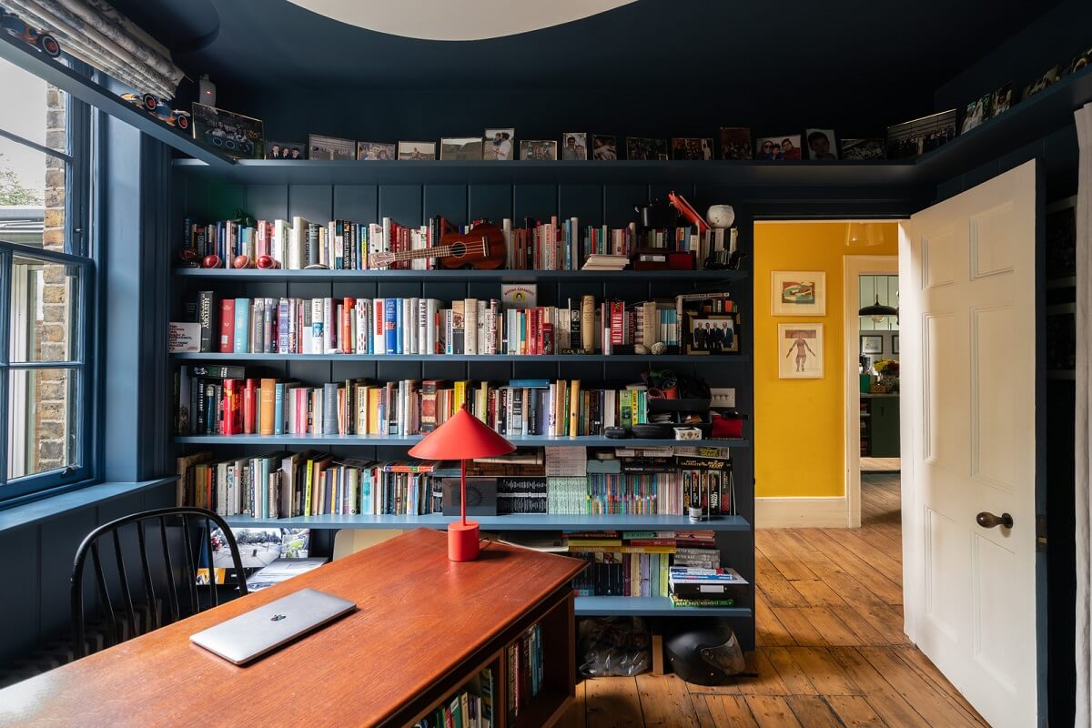 A Beautiful London Family Home with Colorful Accents 5 bookshelves in dark blue color drenched home office nordroom