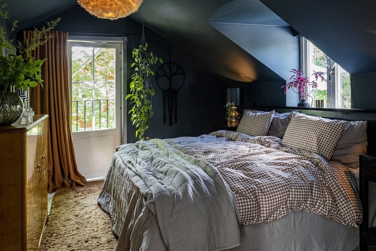 A White Swedish Villa with a Veranda and a Swimming Pool 13 dark blue bedroom with slanted ceiling and bed under dormer window nordroom