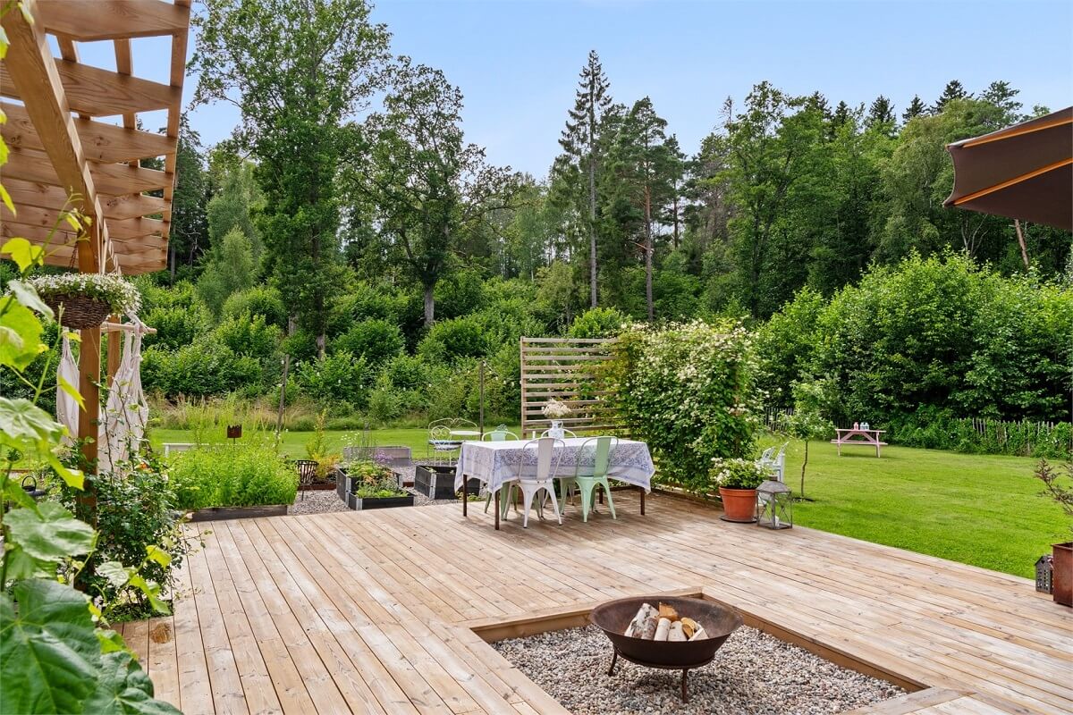 A Bright Open-Plan Swedish Home with a Pink Kitchen 27 garden with large wooden deck and fire pit