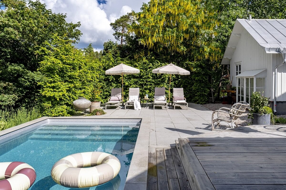 A White Swedish Villa with a Veranda and a Swimming Pool 35 garden with swimming pool and lounge beds