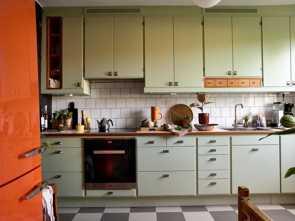 A Charming and Cozy Midcentury Family Apartment in Sweden 11 greeb kitchen checkerboard floor and orange fridge nordroom