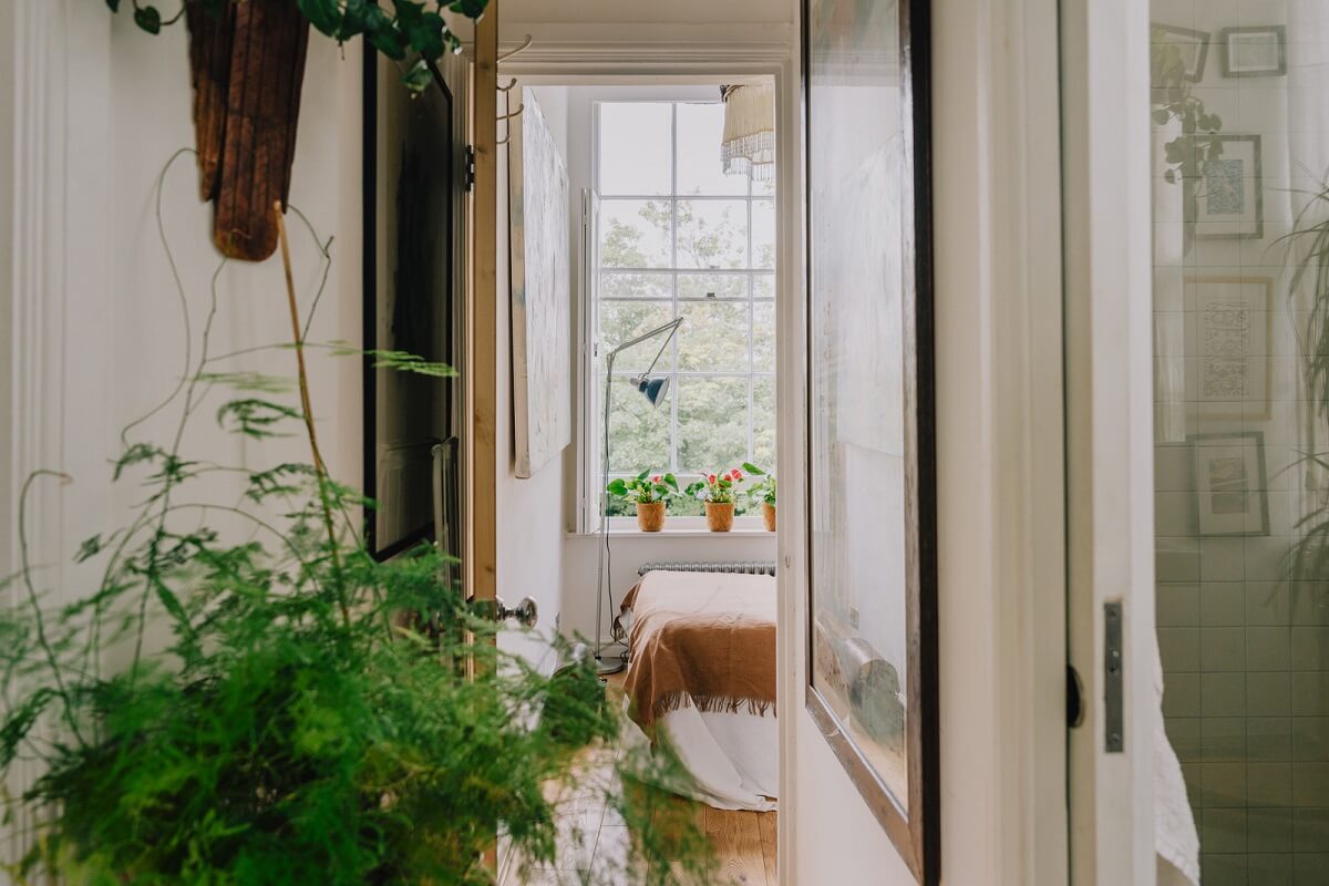 Plants, Art, and a Huge Bay Window in a London Apartment 12 hallway with view of bedroom