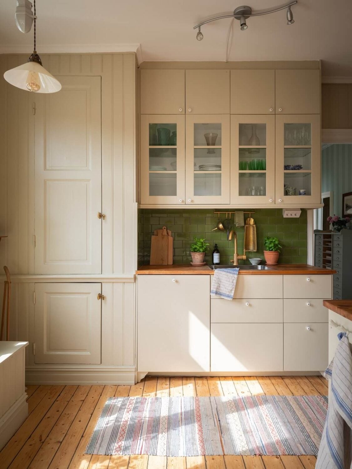 Charming Vintage Country Style in a Family Apartment in Sweden 10 kitchen with cream colored cabinets and green tiles nordroom