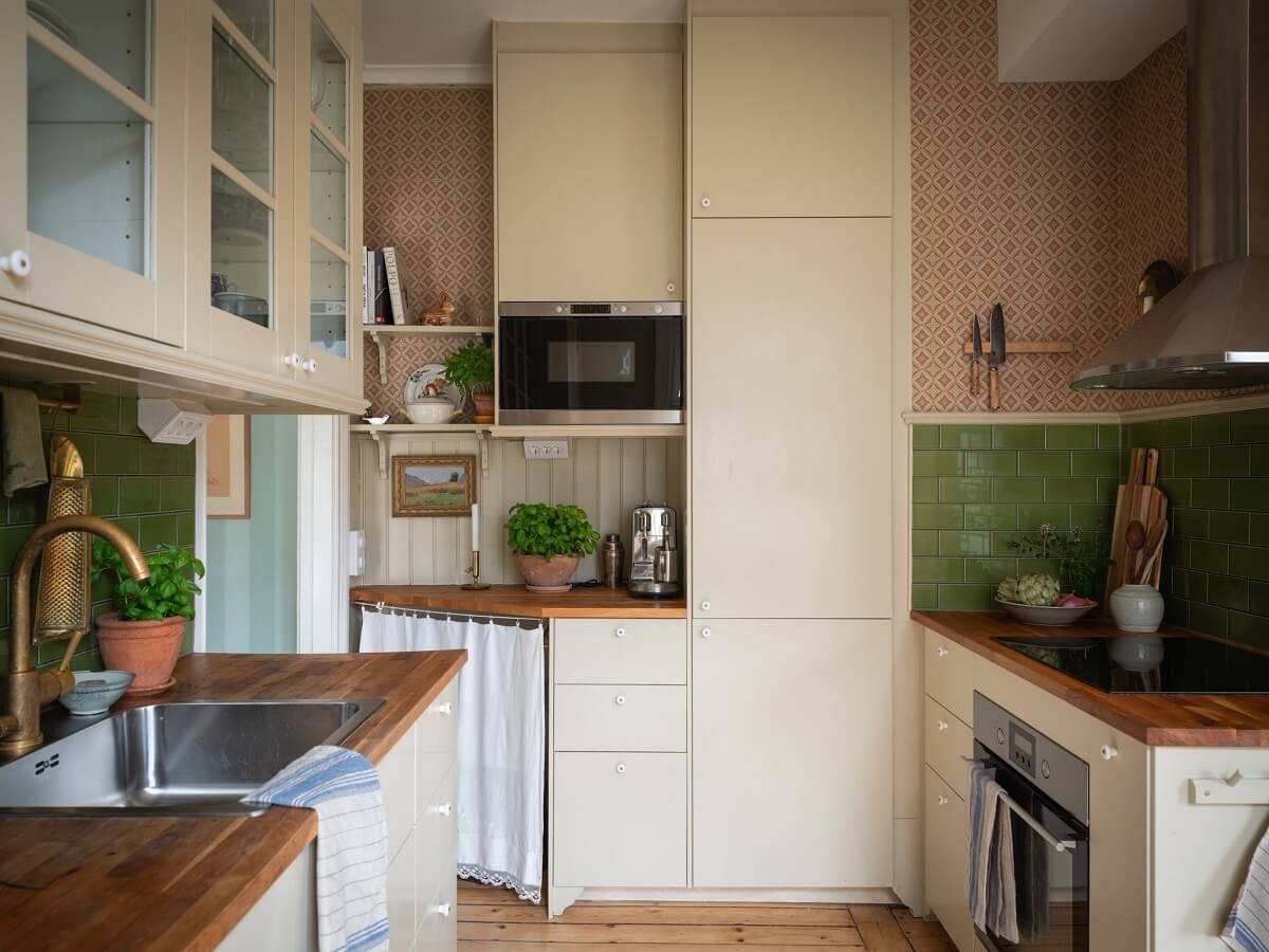 Charming Vintage Country Style in a Family Apartment in Sweden 13 kitchen with cream colored cabinets green tiles and pink walls nordroom