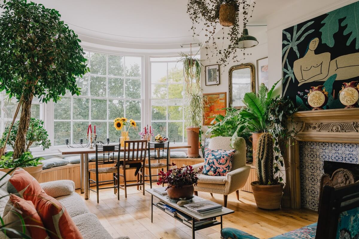 Plants, Art, and a Huge Bay Window in a London Apartment 1 large bay window with built in bench and ornate fireplace living room