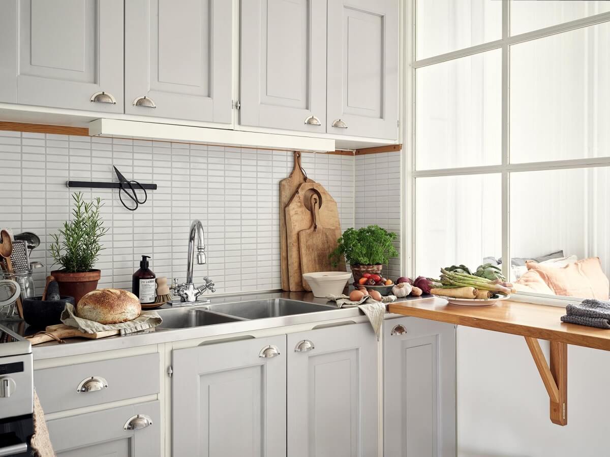 A Small Apartment with a Bright Open-Plan Kitchen & Bedroom 2 light gray kitchen cabinets and bar shelf in front of indow