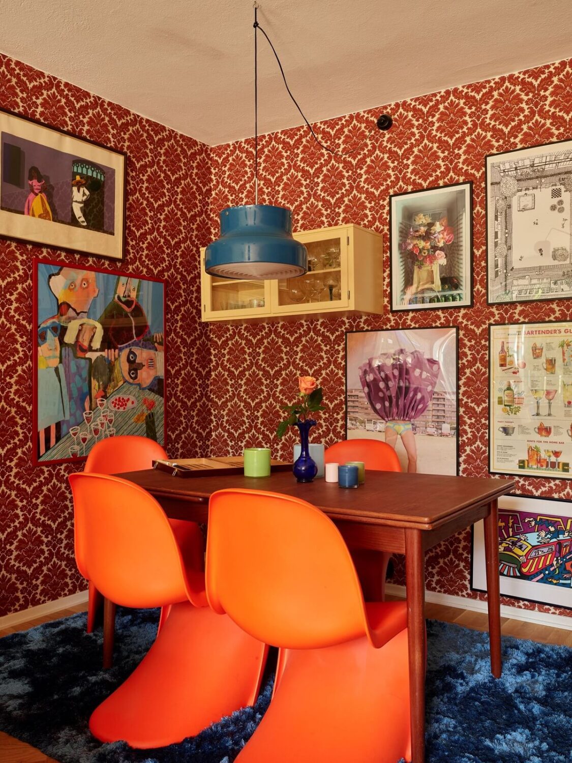 A Colorful Swedish Apartment Inspired by the 50s and 70s 16 orange dining chairs and wallpapered walls with art nordroom