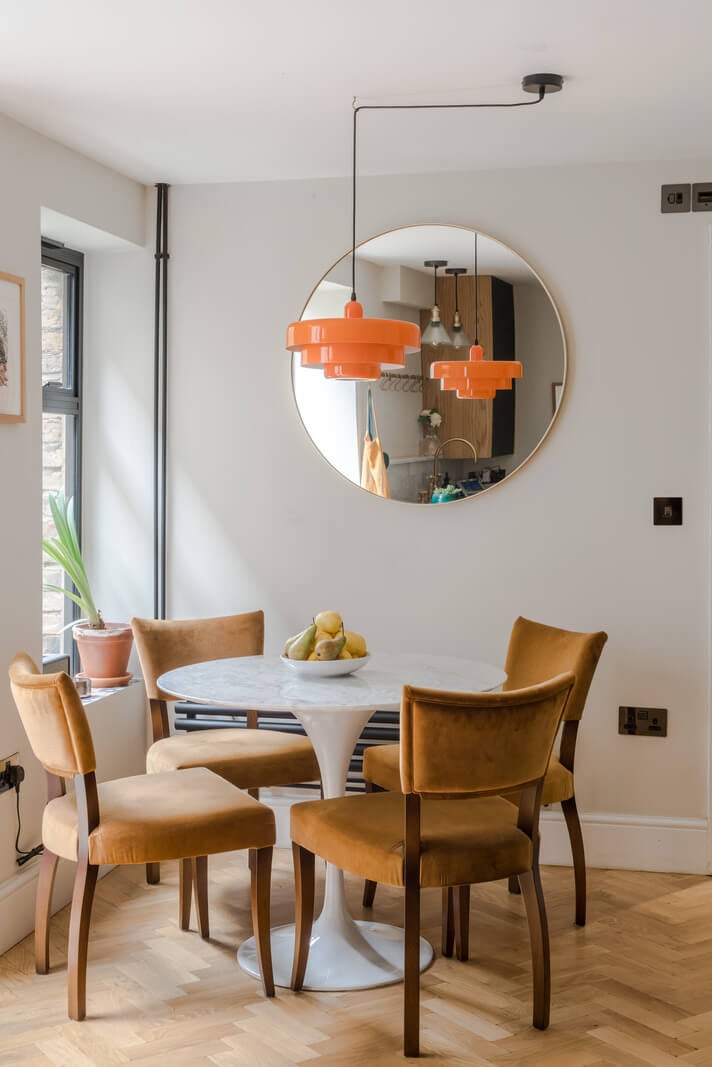 A London Apartment with a Deep Olive Green Kitchen 7 round white dining table with ochre yellow chairs and orange pendant nordroom