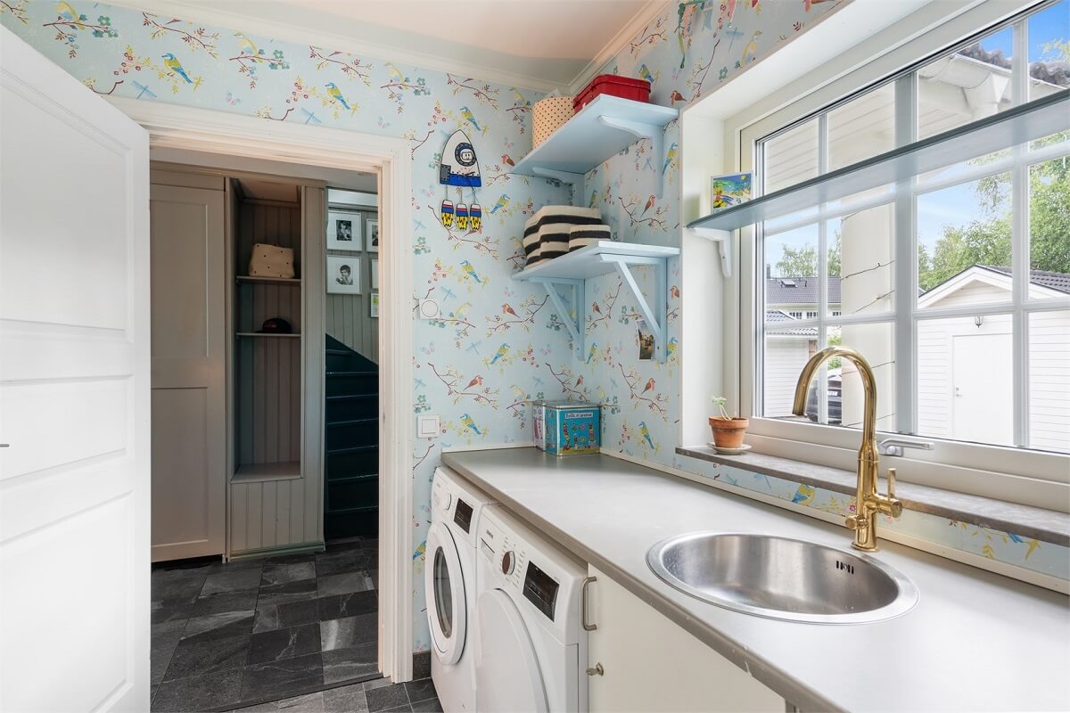 A Bright Open-Plan Swedish Home with a Pink Kitchen 19 utility room with blue wallpaper