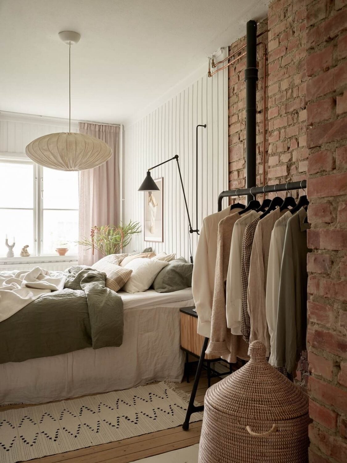 A Swedish Apartment with a Dark Blue Living Room and Exposed Brick 11 bedroom with brick wall and clothing rack