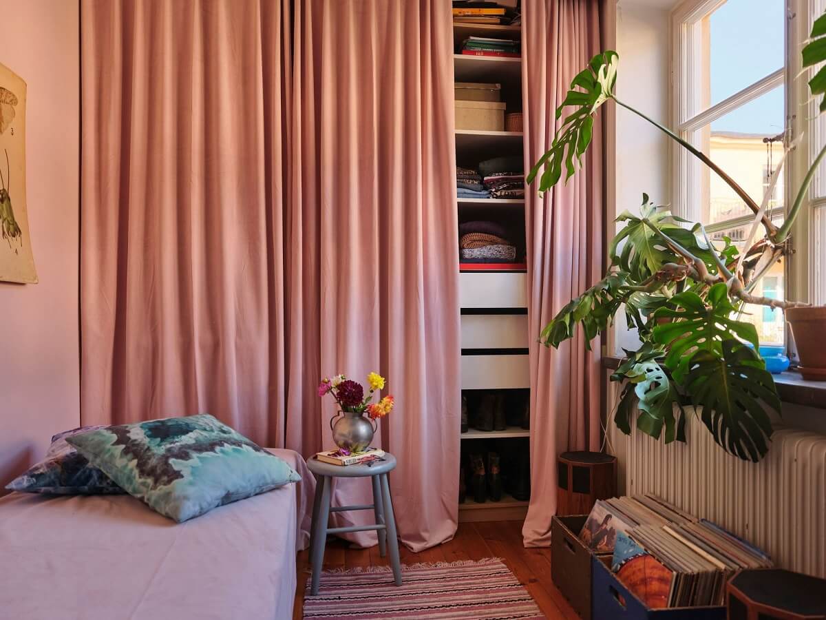 A Charming Small Two-Bedroom Apartment in Stockholm 20 bedroom with floor to ceiling wardrobes hidden by pink curtain nordroom