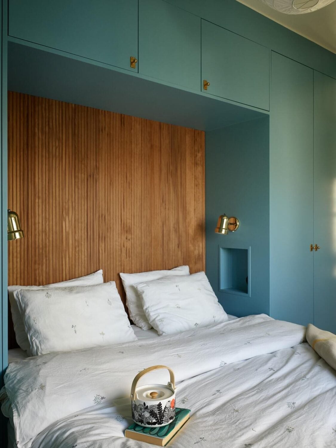 A Midcentury Swedish Apartment with Bold Colors 13 blue bedroom with custom wardrobes around bed