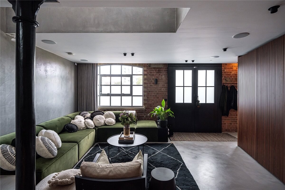 An Industrial, Loft-Style Duplex with Japanese Landscaped Roof Terraces 1 industrial living room with brick wall green corner sofa and wooden cabinets