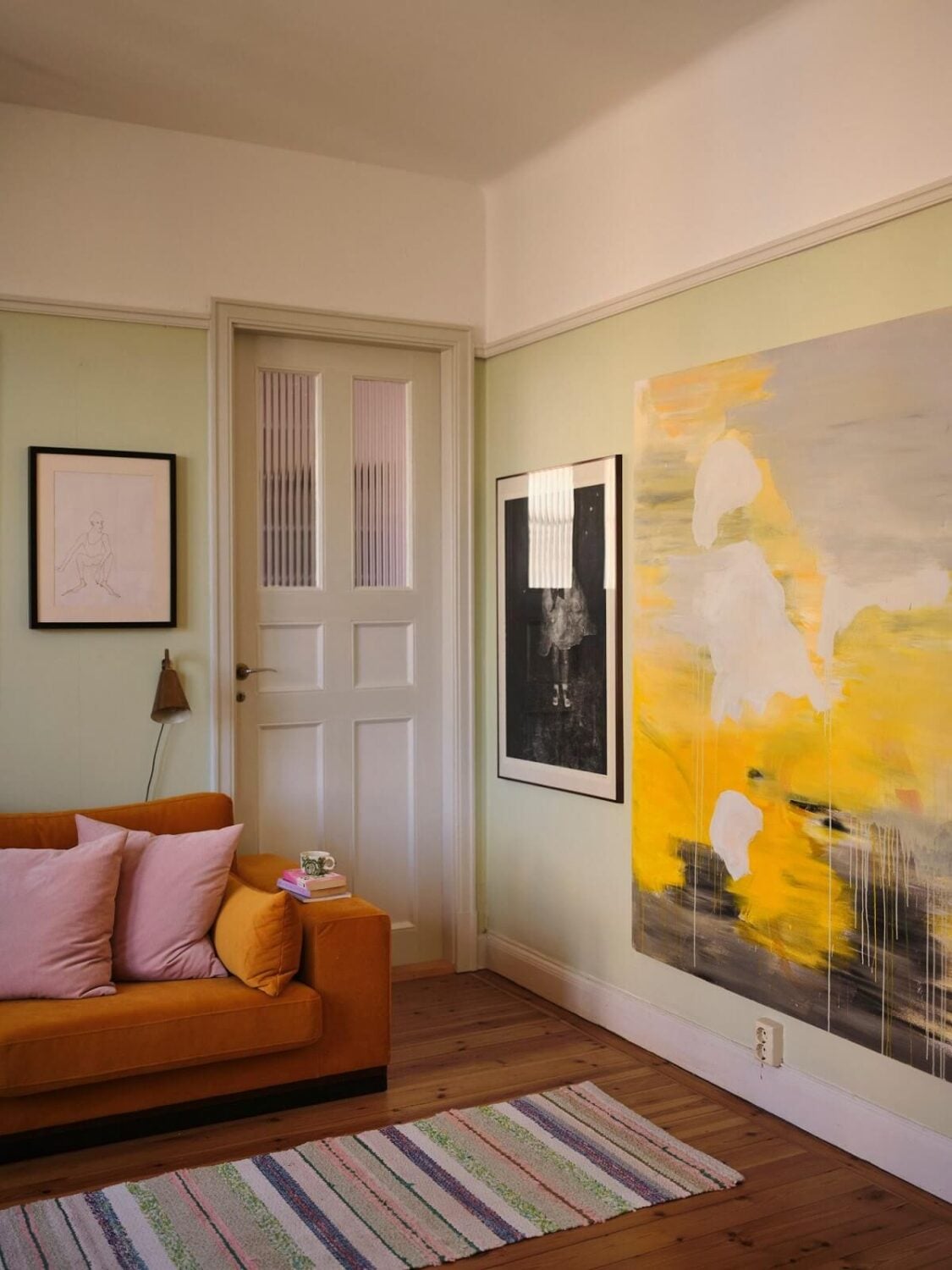 A Charming Small Two-Bedroom Apartment in Stockholm 3 living room with pastel green walls and ochre sofa