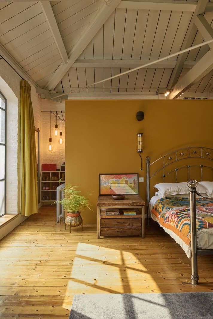 An Industrial and Colorful Warehouse Conversion in London 13 ochre yellow accent wall bedroom