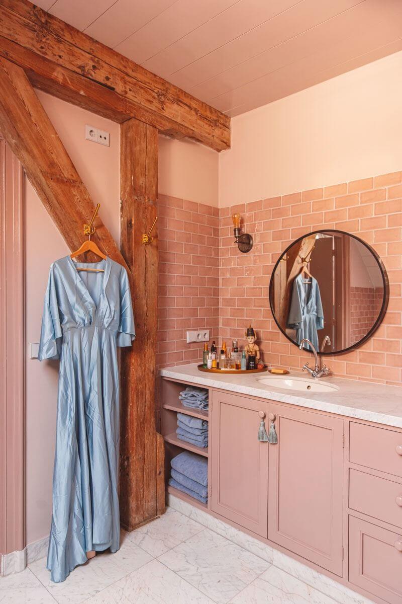 An Eclectic Colorful House in an Old Dutch Farmhouse 25 pink bathroom with exposed wooden beams round mirror