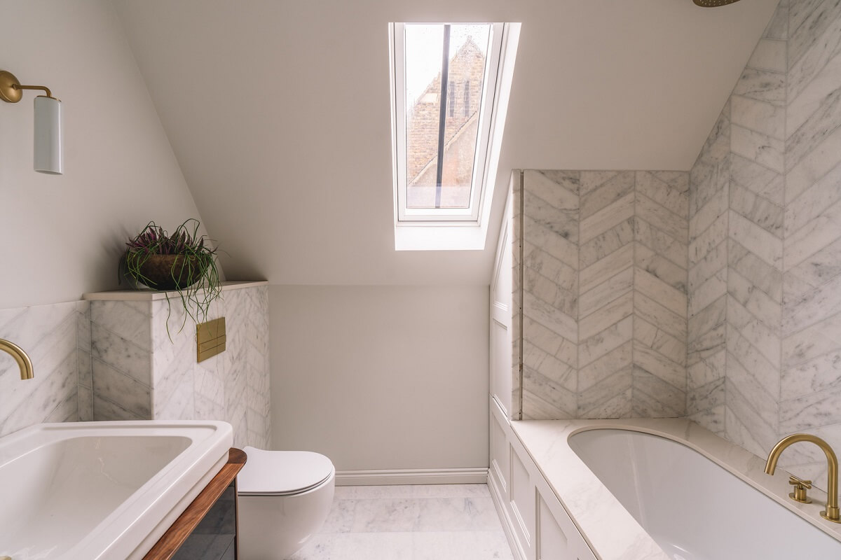 Contemporary Interiors with Limewash Walls in an Old School Building 21 bathroom with slanted ceiling and marble tiles in chevron pattern