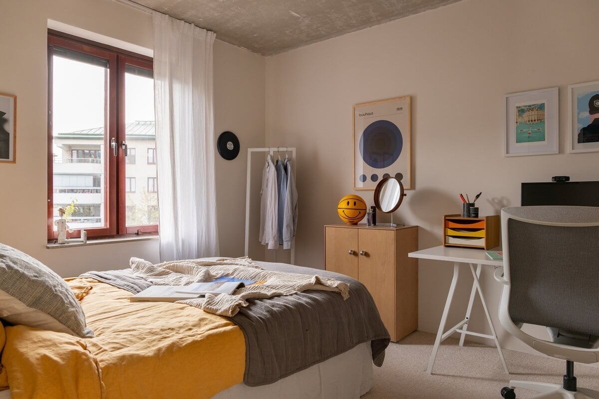 A Light and Modern Stockholm Apartment with Cheerful Color Accents 15 bedroom with desk and concrete ceiling