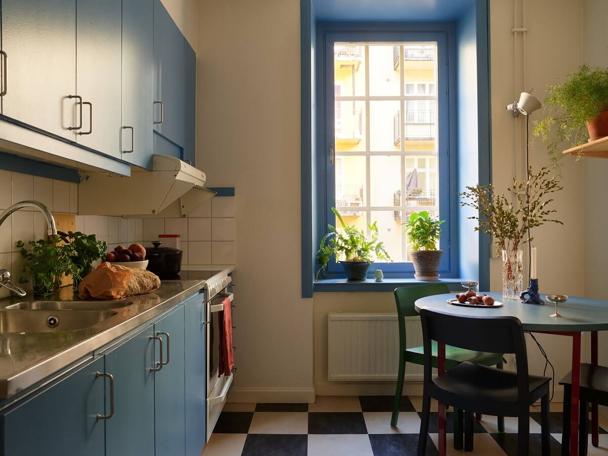 Golden Yellow Walls in a Colorful Swedish Studio Apartment 11 blue kitchen with small round table checkerboard floor nordroom