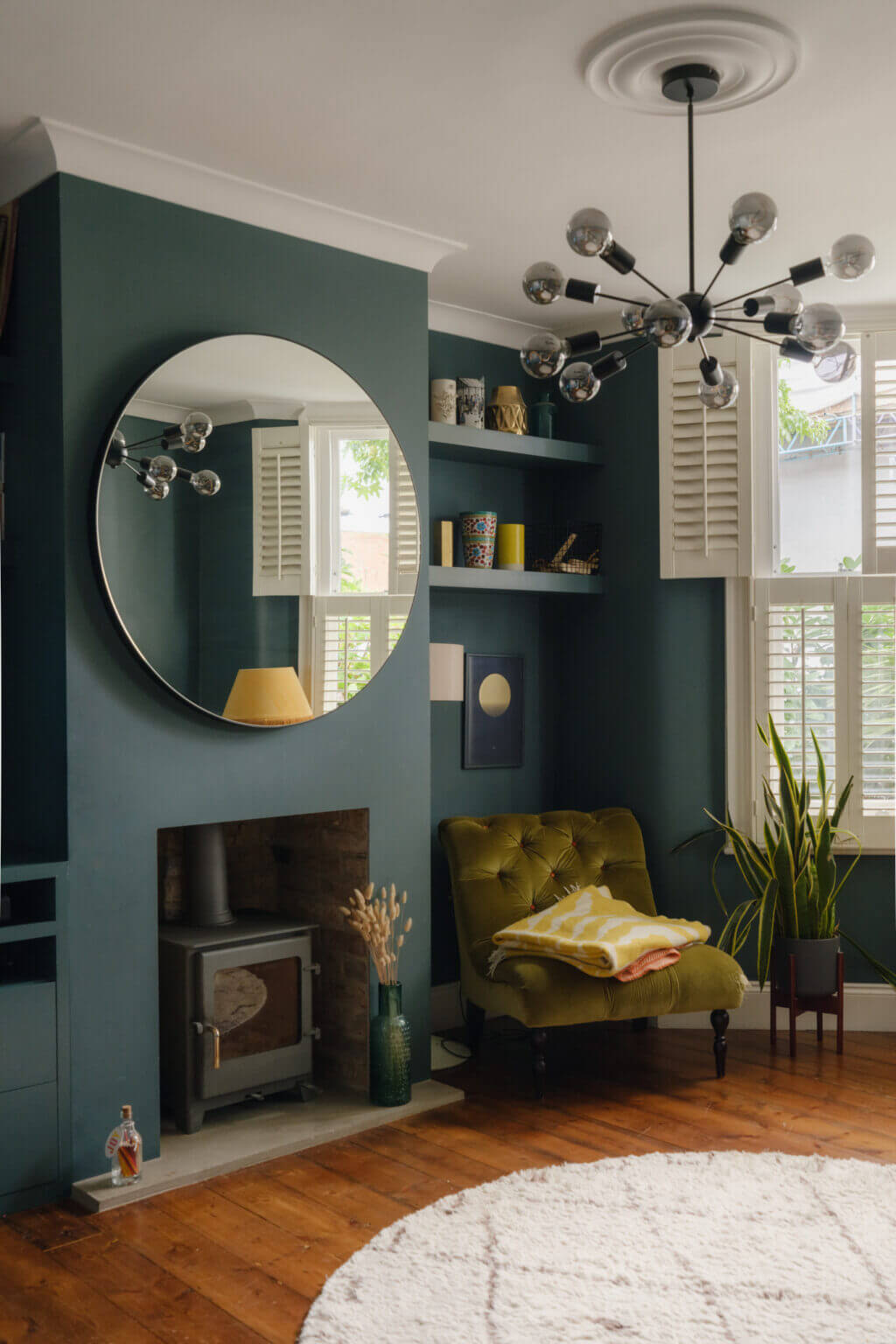 blue living room with wood burner and large round mirror