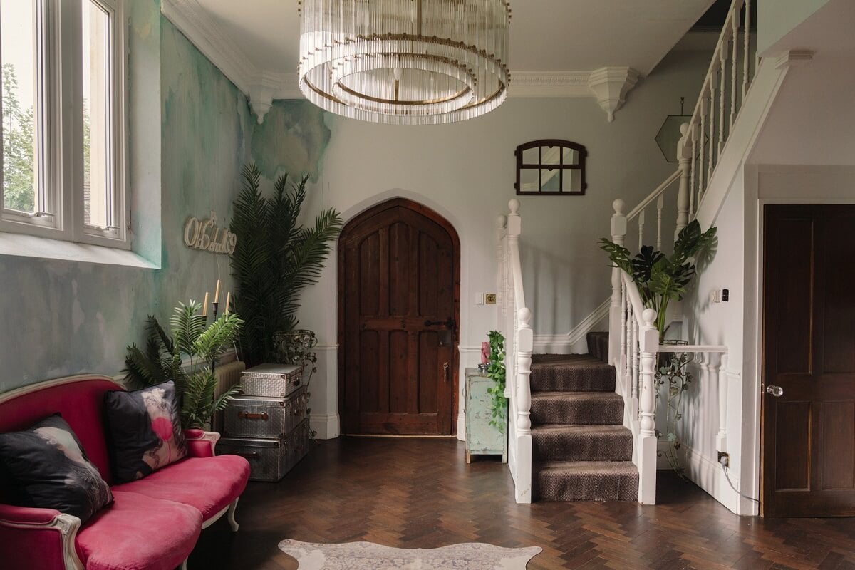 A Colorful Gothic-Style School Conversion in England 5 living space with pink sofa and gothic style wooden door