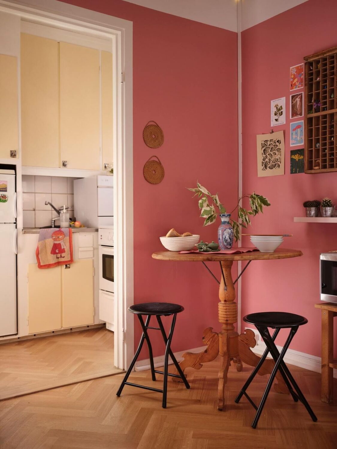A Bold Pink Studio Apartment with a Light Yellow Kitchen 10 pink studio apartment small dining area with round wooden table and stools nordroom