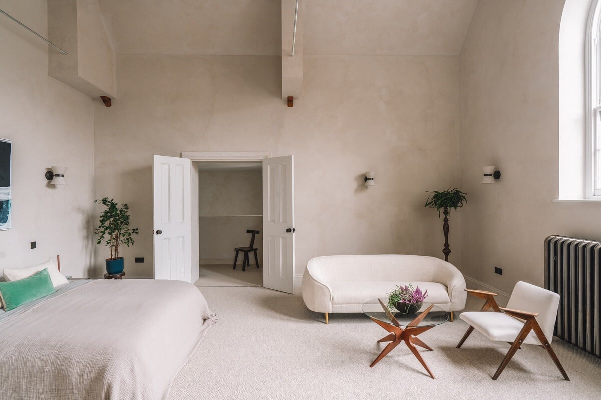 Contemporary Interiors with Limewash Walls in an Old School Building 11 spacious light colored bedroom with seating area