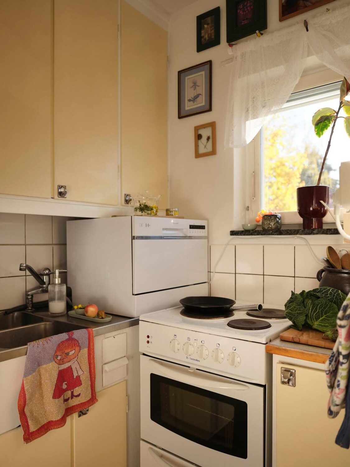 A Bold Pink Studio Apartment with a Light Yellow Kitchen 11 tiny kitchen with butter yellow cabinets