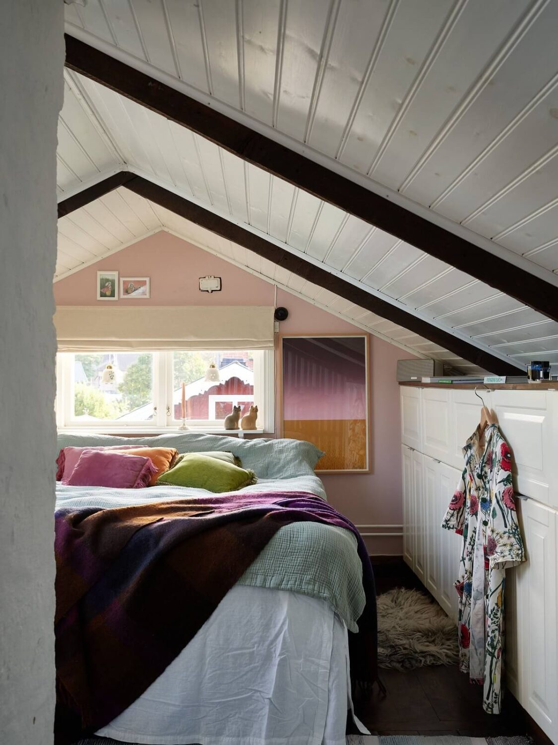 A Charming Swedish Cottage Filled with Art and Color 15 attic bedroom light pink accent wall