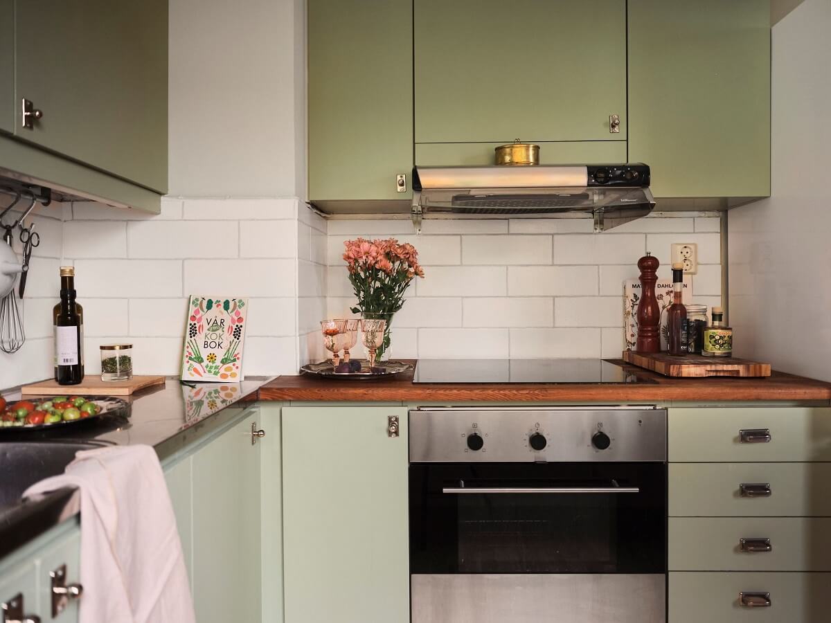A Small Swedish Apartment with a Social and Semi-Open Floorplan 16 green cupboards with wooden countertop