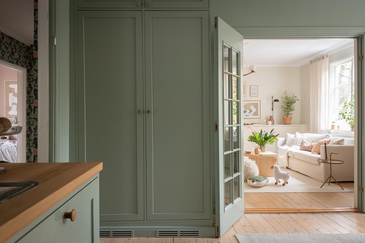 A Swedish Apartment Painted in Calm Beige, Green, and Pink Tones 15 green kitchen built in cabinets