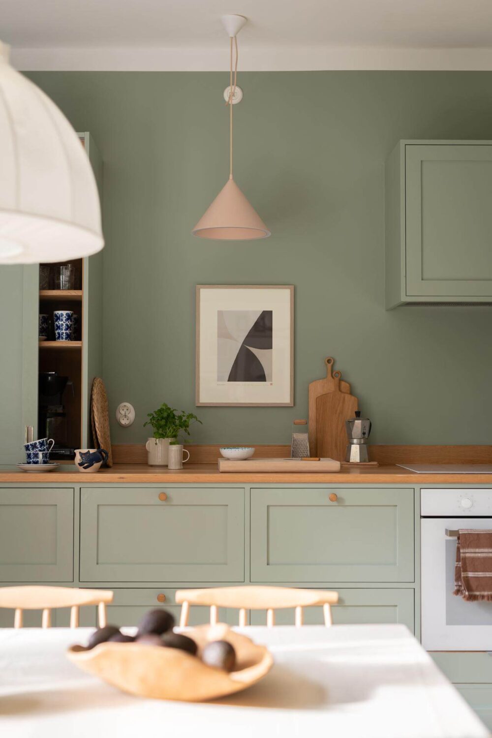 A Swedish Apartment Painted in Calm Beige, Green, and Pink Tones 12 green kitchen detail wooden worktop