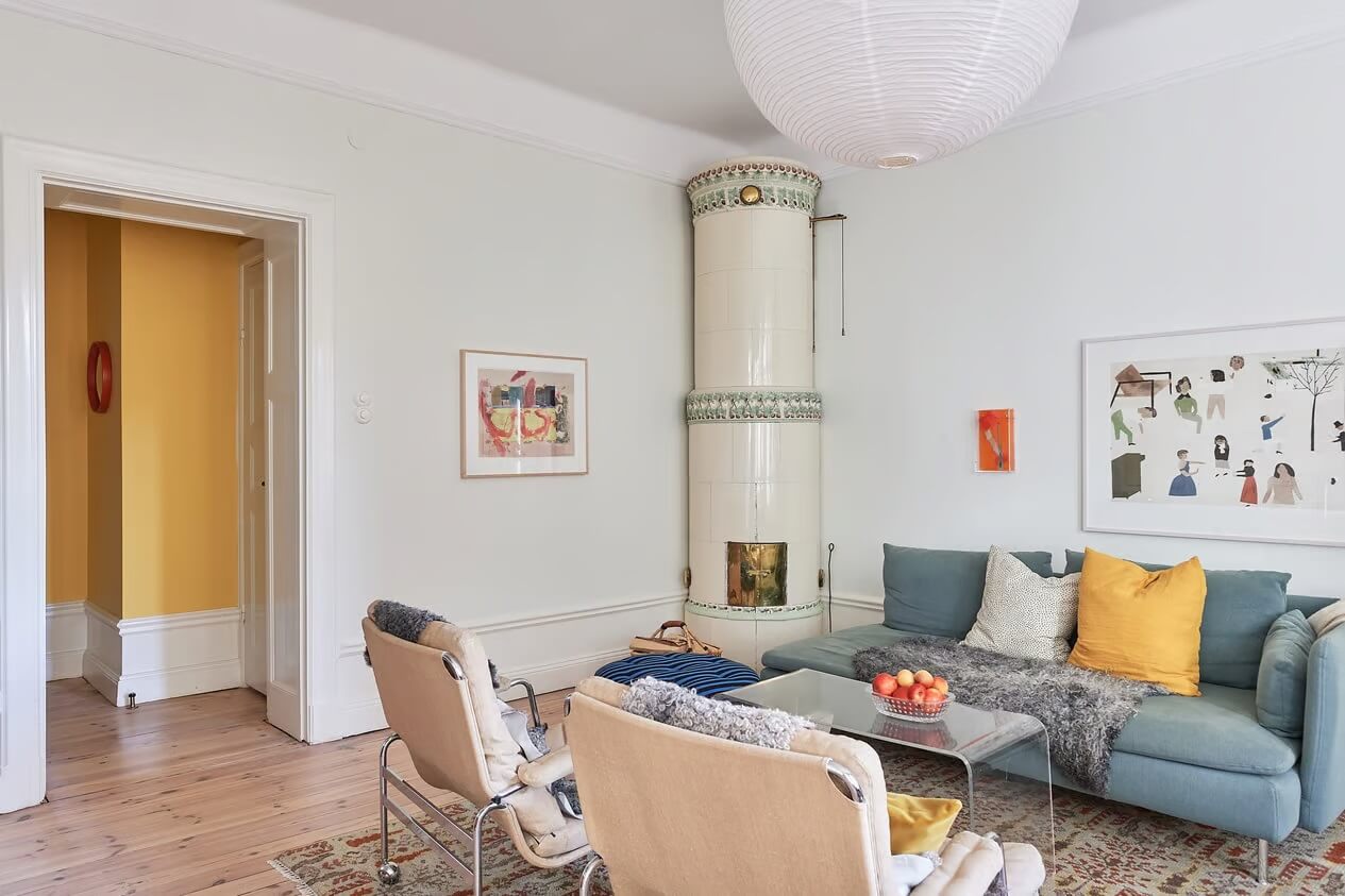 A Light Swedish Apartment with a Yellow Kitchen 3 living room blue sofa fireplace