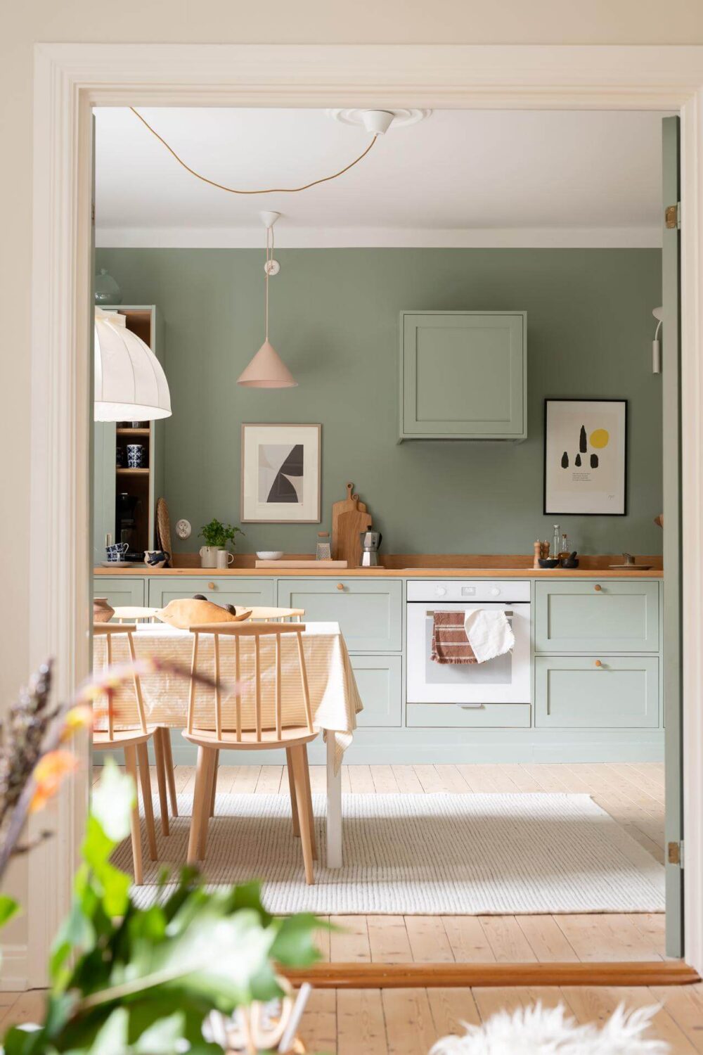 A Swedish Apartment Painted in Calm Beige, Green, and Pink Tones 7 peek into kitchen