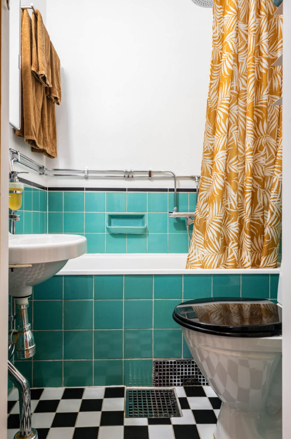 A Vibrant, Colorful Midcentury Apartment in Malmö 20 a colorful bathroom with green tiles and ochre yellow curtain