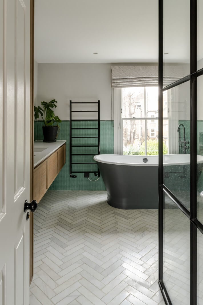 A Beautiful Extended Victorian Family Home in London 13 bathroom with freestanding bath green wall tiles and herringbone floor tiles nordroom