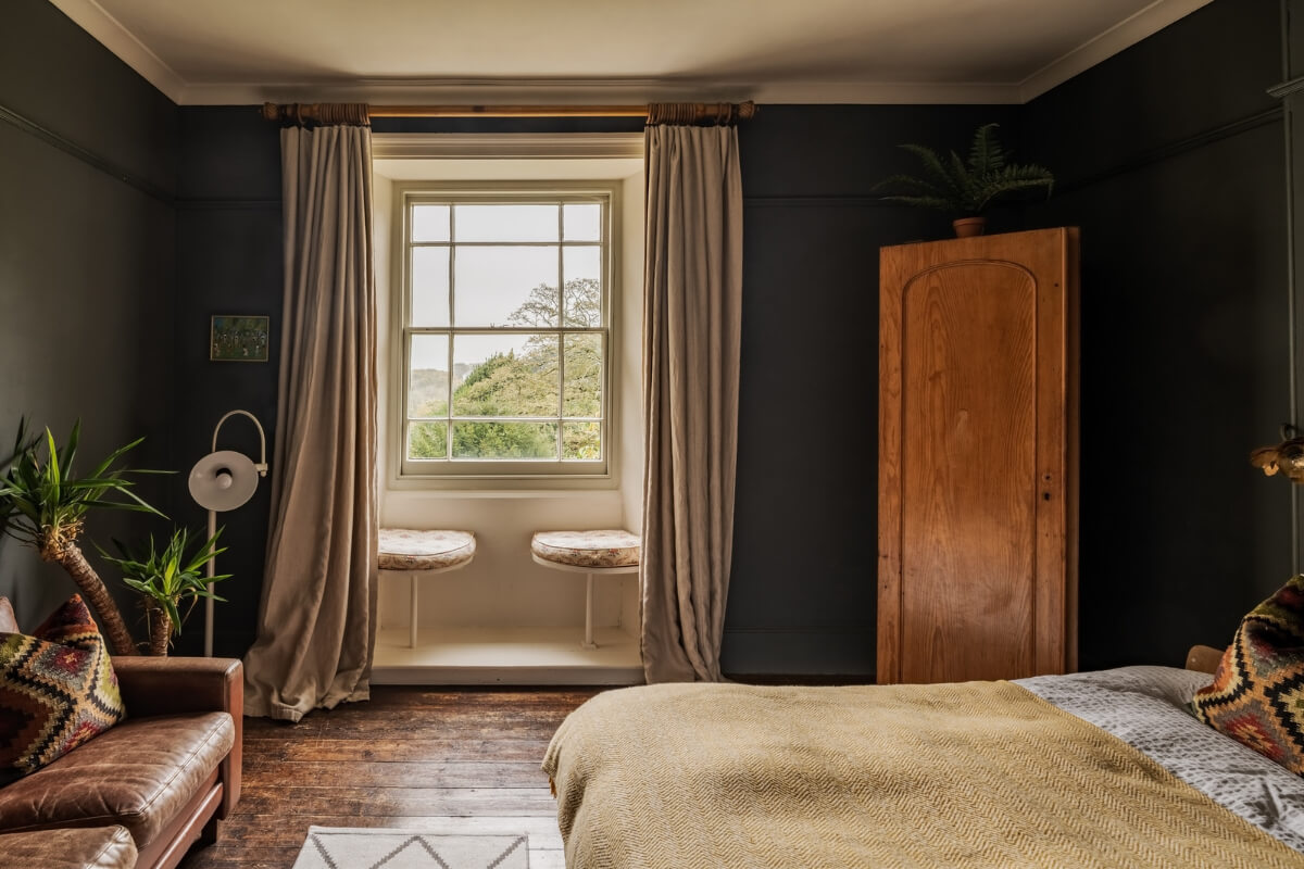 A Strong Color Palette in a Unique Country House in Cornwall 16 black bedroom with bay window with seating