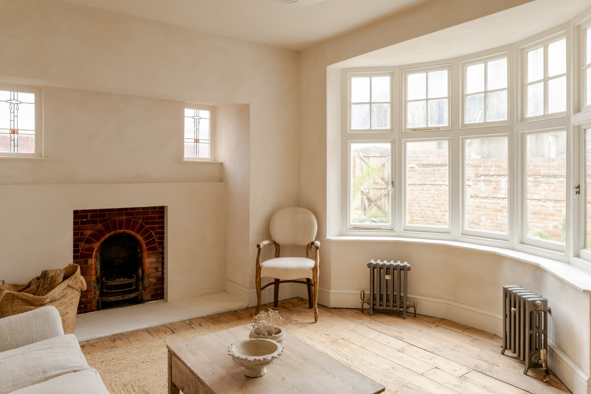brick fireplace and bay window in serene living room with wooden floor and plaster walls nordroom