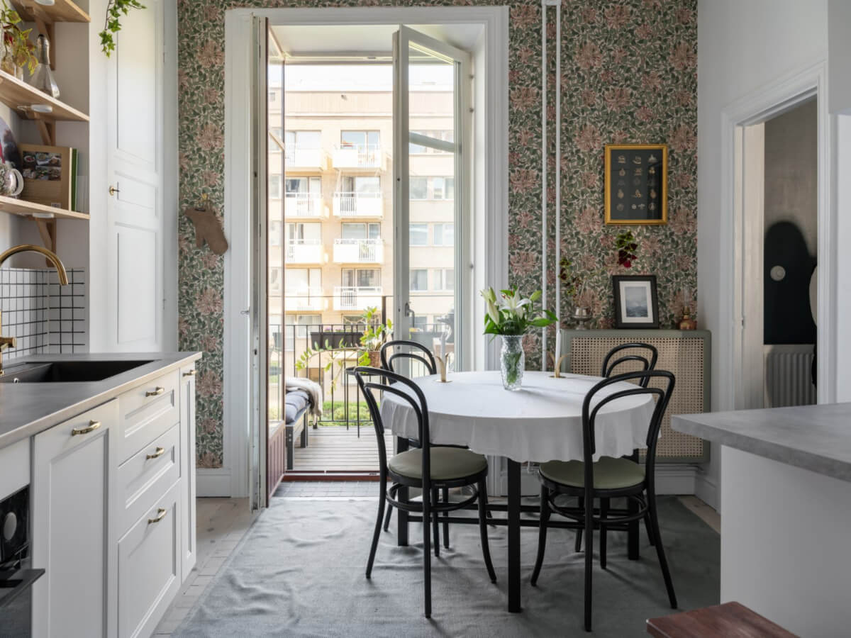 A Classic Studio Apartment with an Industrial Glass Room Divider 11 classic white kitchen with shelves a round table and floral wallpaper nordroom